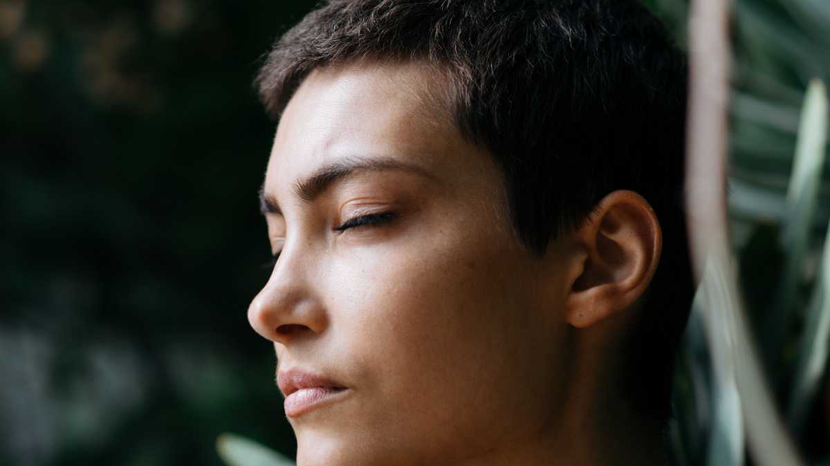 A person with their eyes closed amidst nature